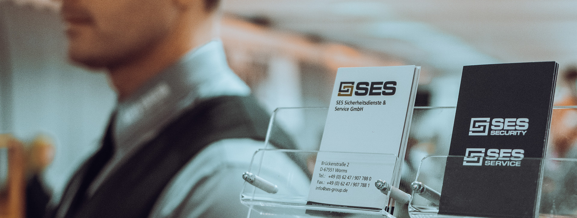 Visitenkarten von SES Sicherheitsdienste & Service GmbH auf einem Tisch mit einem unscharfen Hintergrund