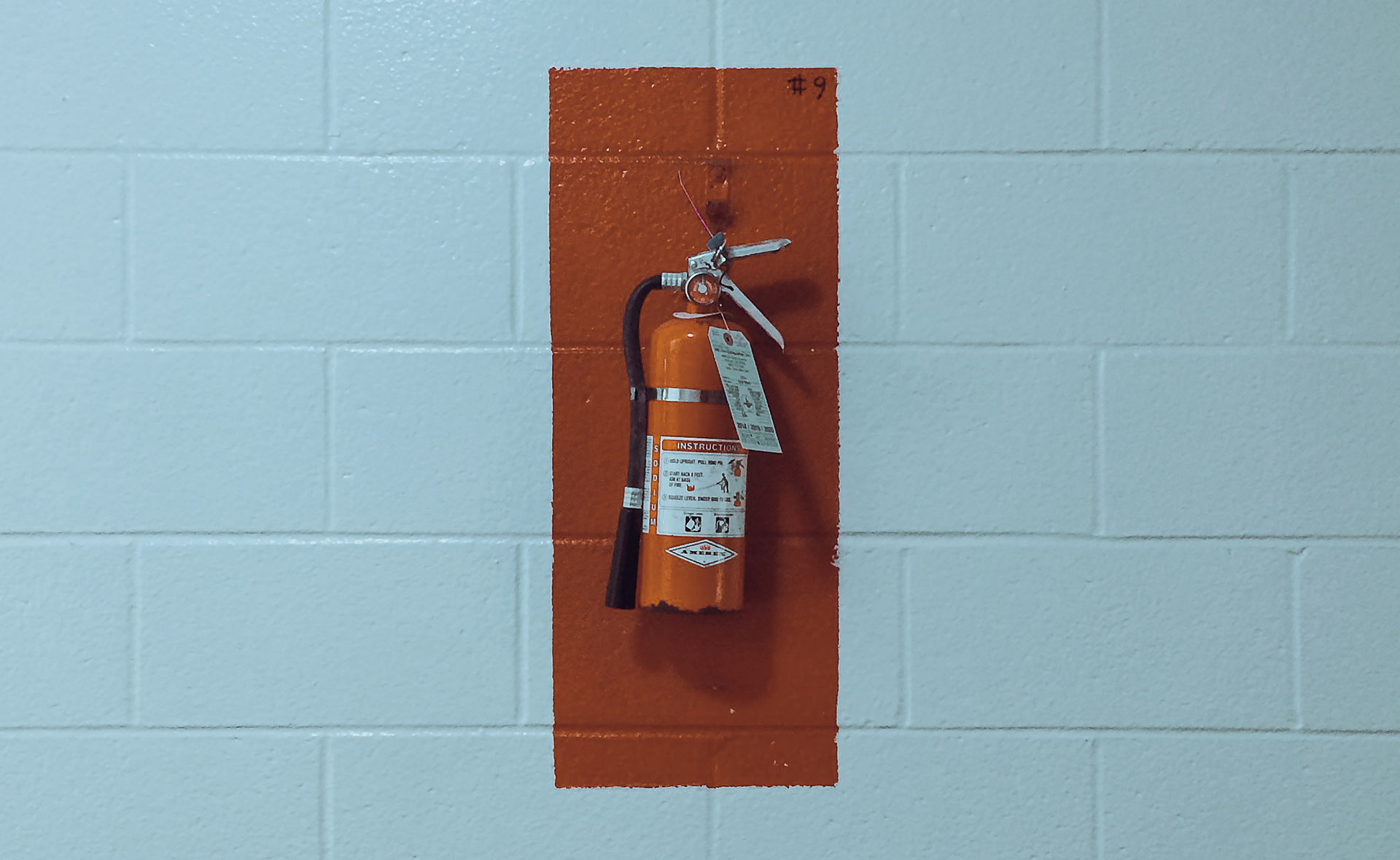 Feuerlöscher montiert an einer Wand mit roter Sicherheitsmarkierung