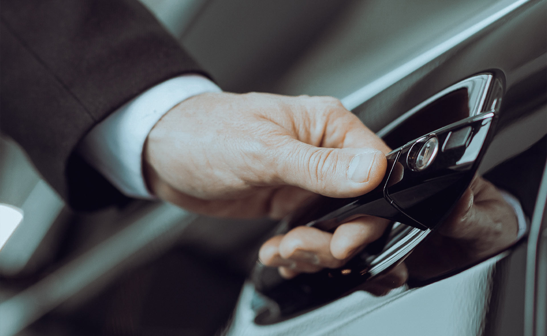 Hand eines SES Service Chauffeurs öffnet Autotür mit Schlüsselanhänger